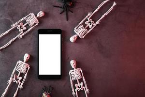 des squelettes décoratifs se trouvent près du smartphone sur un fond sombre. photo