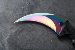 un poignard avec une lame en acier avec un dégradé de couleur sur fond noir. photo
