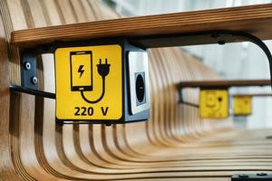 une prise avec un panneau de charge d'appareil sur un banc en bois à l'aéroport. photo