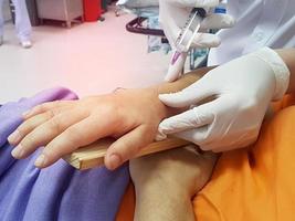 un médecin perce le poignet avec une seringue pour injection, poignet cassé suite à un accident photo