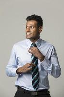 homme d'affaires indien heureux ajustant sa cravate. photo