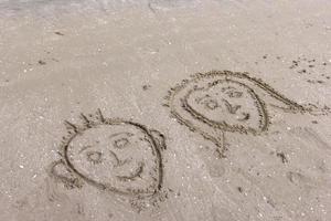 visage de garçons et de filles s'appuyant sur le sable de la plage photo