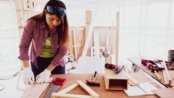 menuisier féminin utilisant un ruban à mesurer pour mesurer la taille de la planche. photo