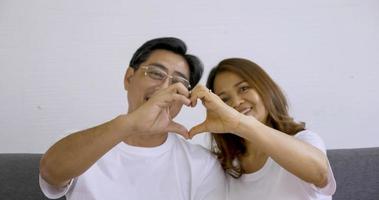 couple heureux faisant le coeur de la main ensemble dans la chambre. photo