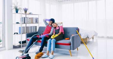 heureux mari et femme assis sur un canapé après avoir nettoyé la chambre ensemble. photo