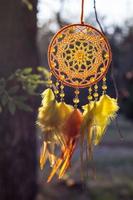 attrape-rêves fait à la main avec des fils de plumes et des cordes de perles suspendues photo