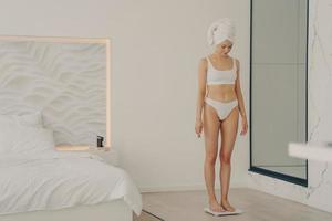 jolie jeune fille mince debout sur une balance dans la chambre photo