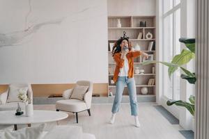 fille excitée s'amusant follement dans son salon. une femme européenne heureuse chante à la maison. photo