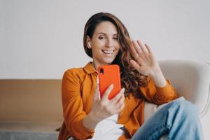 une fille européenne heureuse a un appel vidéo à la maison. écouteurs sans fil utilisés lors d'une conférence en ligne. photo