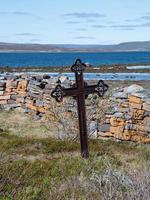 une vieille pierre tombale en métal près d'un mur de pierre empilé à l'église de nesseby dans le nord de la norvège. photo