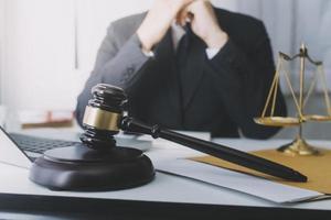 concept de justice et de droit. juge masculin dans une salle d'audience avec le marteau, travaillant avec, clavier d'ordinateur et d'accueil, lunettes, sur table à la lumière du matin photo