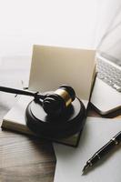 concept de justice et de droit. juge masculin dans une salle d'audience avec le marteau, travaillant avec, clavier d'ordinateur et d'accueil, lunettes, sur table à la lumière du matin photo