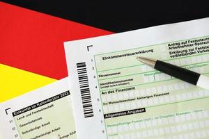 Formulaire de déclaration de déclaration de revenus annuel allemand avec un stylo sur le drapeau de près. le concept de déclaration fiscale en allemagne photo