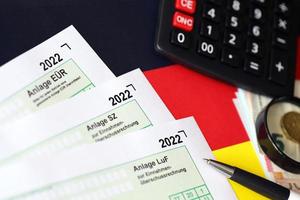 allemand différents formulaires vierges de déclaration fiscale - anlage eur, anlage sz et anlage luf. les documents se trouvent avec une calculatrice, un stylo et de l'argent européen photo