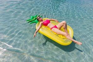 jeune femme s'amusant et riant sur un matelas gonflable de flotteur de piscine flamingo. jolie femme une journée d'été dans la piscine. photo