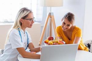 nutritionniste professionnel rencontrant un patient au bureau et des fruits sains avec un ruban à mesurer, une alimentation saine et un concept de régime. bureau de nutritionniste avec fruits sains, jus et ruban à mesurer. photo