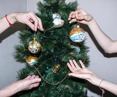 une main féminine décore le sapin de noël avec des jouets de noël et du nouvel an. la main de la femme décore le sapin de noël avec des guirlandes. photo