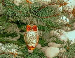 le hibou de jouet de noël est suspendu à une branche enneigée d'un arbre de noël sur un fond festif de bokeh de neige blanche avec espace de copie. photo