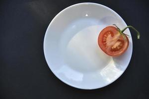 belle tomate mûre sur une vue de dessus de plaque blanche. délicieuses tomates nature morte. photo