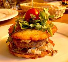 burger dranburger à base de crêpes de pommes de terre, avec escalope, roquette, fromage, tomate. nourriture créative. photo