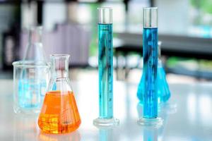 des produits chimiques orange dans des flacons et des produits chimiques bleus dans des tubes cylindriques placés sur la table ont été préparés pour des expériences chimiques dans des laboratoires de chimie. photo