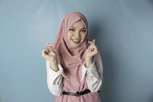 une jolie jeune femme musulmane asiatique portant un hijab rose se sent heureuse et un geste de coeur aux formes romantiques exprime des sentiments tendres photo