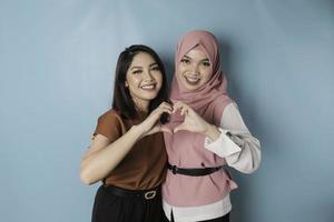 deux jolies jeunes femmes asiatiques se sentent heureuses et un geste de coeur aux formes romantiques exprime des sentiments tendres et un concept d'amitié photo