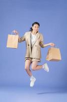 heureuse jeune femme avec des sacs à provisions sur fond violet photo