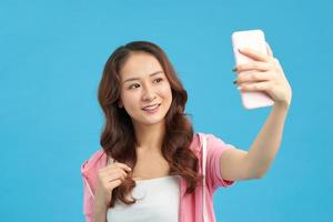 femme asiatique prenant selfie sur smartphone isolé sur fond bleu photo