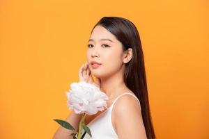 belle jeune femme avec une fleur rose isolée sur jaune photo