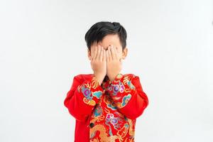 enfant asiatique couvert les yeux avec les mains. portrait de jeune garçon isolé sur fond blanc. photo