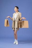 heureuse jeune femme avec des sacs à provisions sur fond violet photo