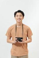 photographe confiant. beau jeune homme tenant un appareil photo numérique et souriant en se tenant debout sur fond blanc