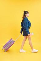 notion de voyage. femme heureuse fille avec valise et passeport sur fond de couleur jaune photo