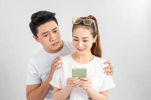 jeune garçon asiatique espionnant le téléphone portable de son partenaire sur fond blanc isolé photo