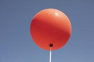 boule rouge contre le ciel. ballon rond de couleur rouge sur bâton. détails des vacances. photo