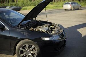 voiture avec capot ouvert. le transport se tient sur le côté de la route. moteur cassé. photo