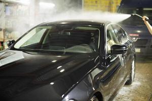 Lave-Auto. voiture noire dans le lave-auto. jet d'eau chaude. photo