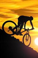 une silhouette d'un cycliste descendant de la montagne le soir. photo