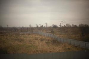 clôture dans le champ. terrain vide clôturé. la clôture en acier est longue. photo