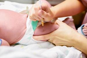 l'image des mains d'une infirmière utilise une seringue pour vacciner progressivement la jambe du bébé. photo