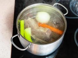 bouillon de boeuf mijoté dans une marmite sur une cuisinière en céramique photo