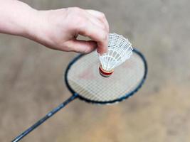 main avec volant blanc sur une raquette de badminton photo