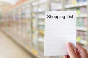 Main tenir le papier de la liste de courses au-dessus de l'allée du supermarché photo