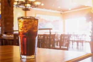 verre de cola avec de la glace sur une table en bois en arrière-plan du restaurant photo