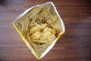 Chips de pommes de terre dans un sac à collation ouvert en gros plan sur le sol de la table photo