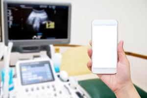 tenir la main smartphone avec salle médicale avec équipement à ultrasons photo