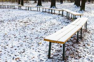 bancs en bois recouverts de la première neige dans le parc photo