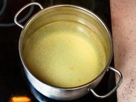 bouillon de boeuf gras clair dans une marmite en acier photo