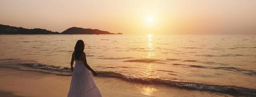 jeune femme solitaire marchant et profitant du magnifique coucher de soleil sur la plage tranquille, voyage en vacances d'été concept, panorama de la bannière photo